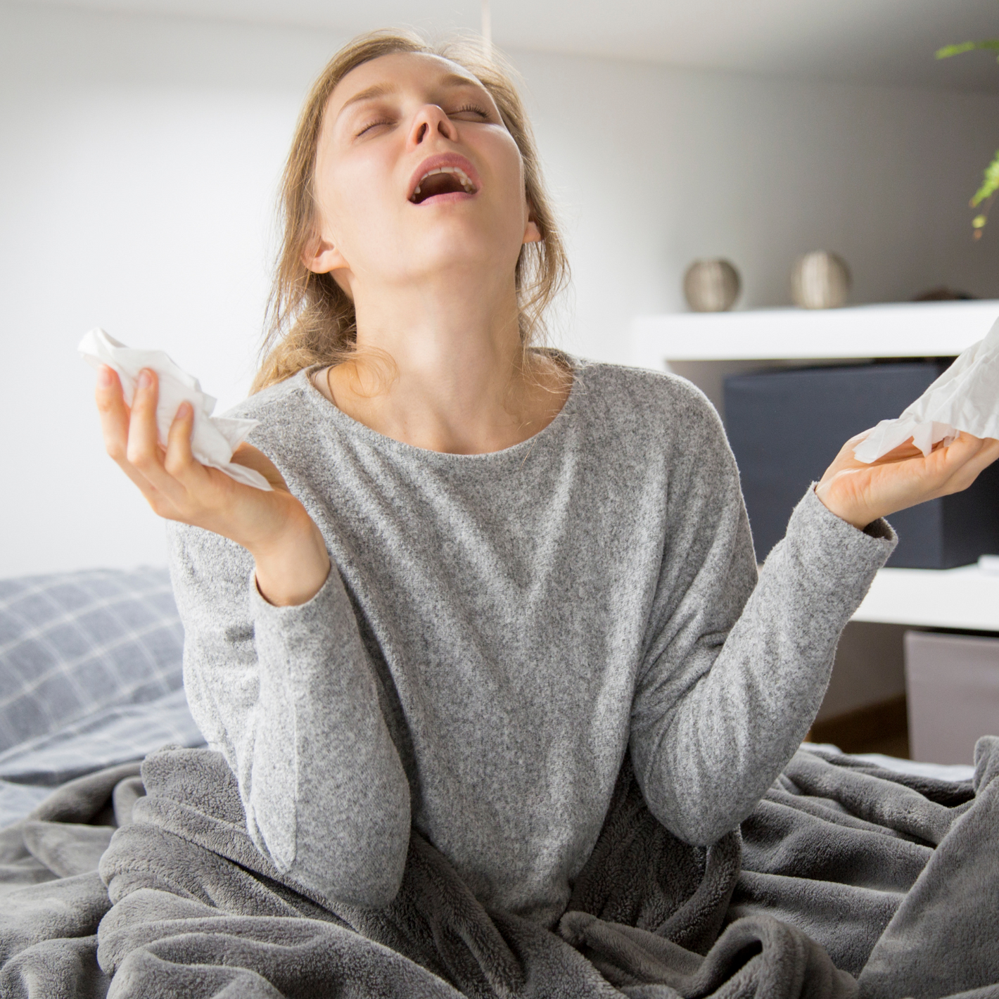 Frau mit Taschentüchern in der Hand atmet durch den Mund uns schaut erleichtert mit geschlossenen Augen.